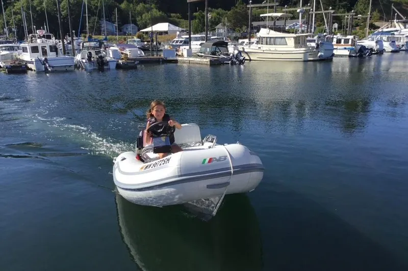 Slide: The Image of Child steering a small inflatable boat in a marina, surrounded by various docked boats. - 82