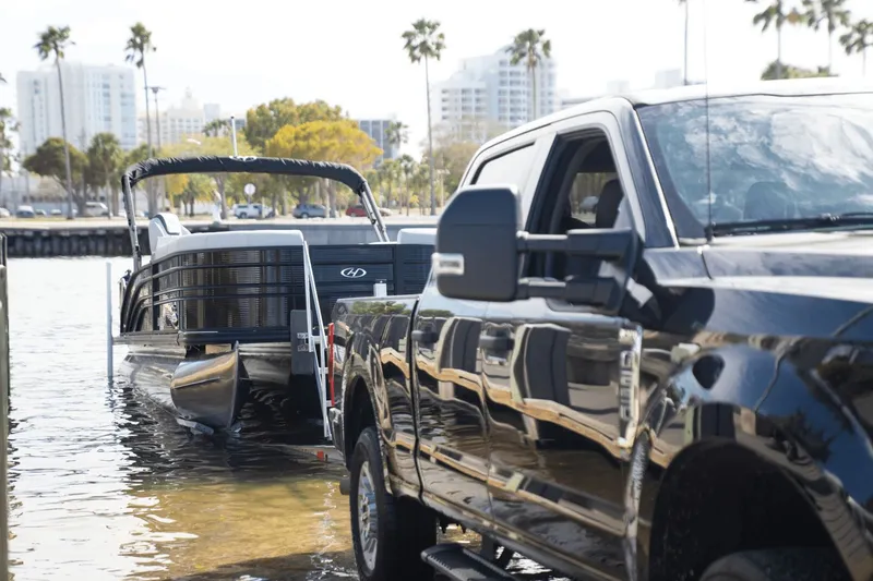 Slide: The Image of 2026 Harris Sunliner 230 boat being launched by a black truck. - 10