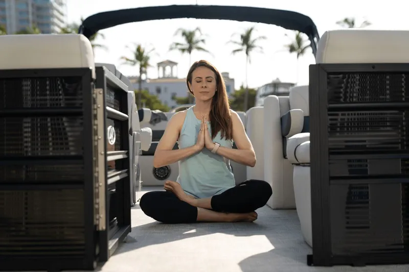 Slide: The Image of Woman meditating on Harris Sunliner 230 pontoon boat, 2026 model. - 13