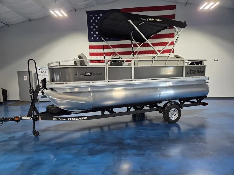Slide: The Image of 2026 Sun Tracker BB 18 DLX pontoon boat on trailer, indoors with American flag backdrop. - 3