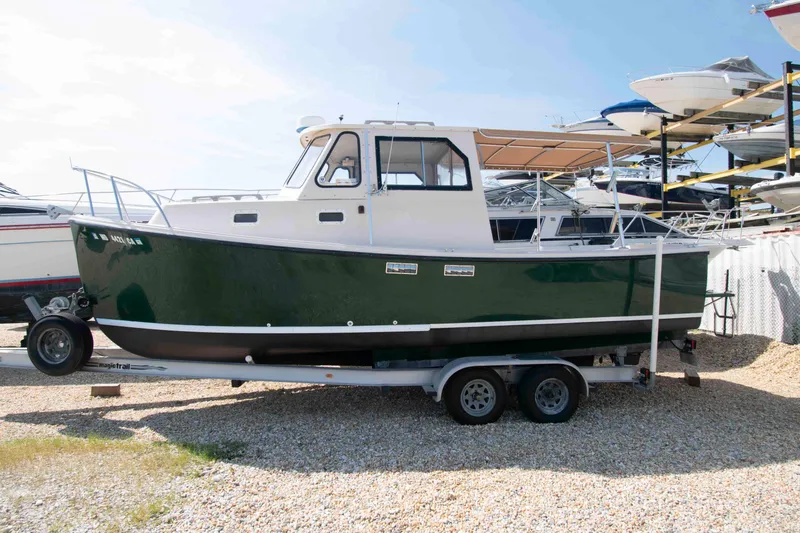 The Image of 2005 Atlas Boat Works Acadia 25 on trailer, green hull, parked in boatyard. - 0