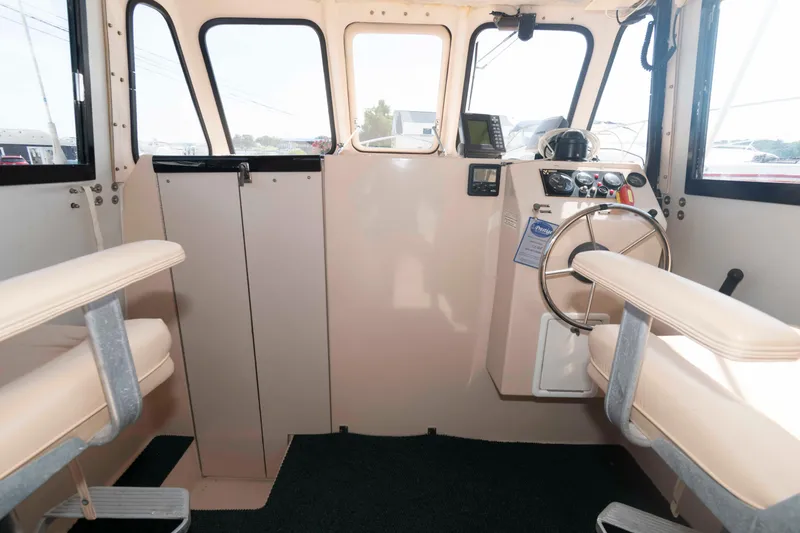 Slide: The Image of Interior of 2005 Atlas Boat Works Acadia 25, featuring helm and seating area. - 7