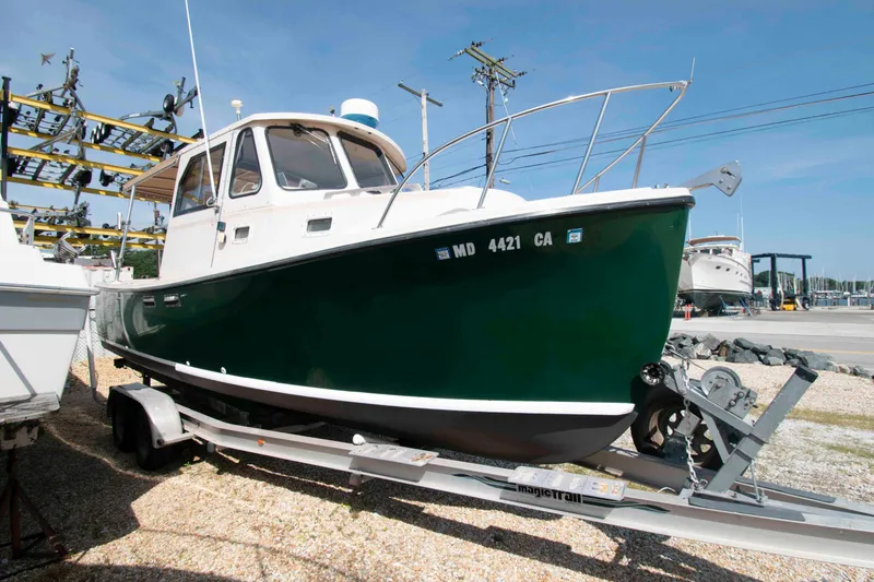 Slide: The Image of 2005 Atlas Boat Works Acadia 25 on trailer, green hull, parked outdoors. - 2