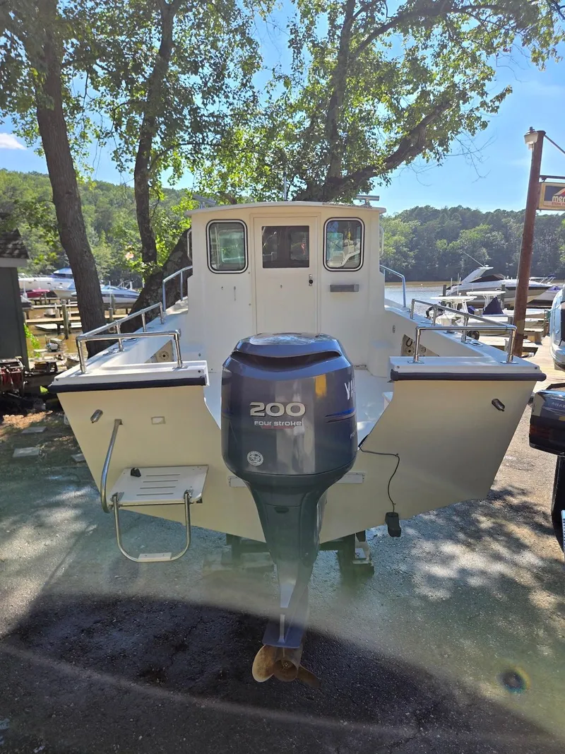Slide: The Image of 2003 Parker 2120 Sport Cabin boat with Yamaha 200 engine, docked near a scenic lake. - 4