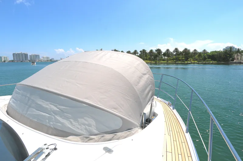 Slide: The Image of 2020 Azimut 55 yacht with covered deck, cruising near palm-lined shore. - 19
