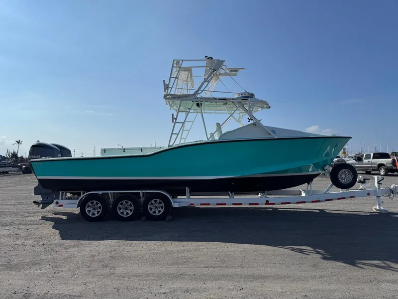 Slide: The Image of Custom Ocean Master 2018 boat on trailer, turquoise hull, clear sky background. - 12