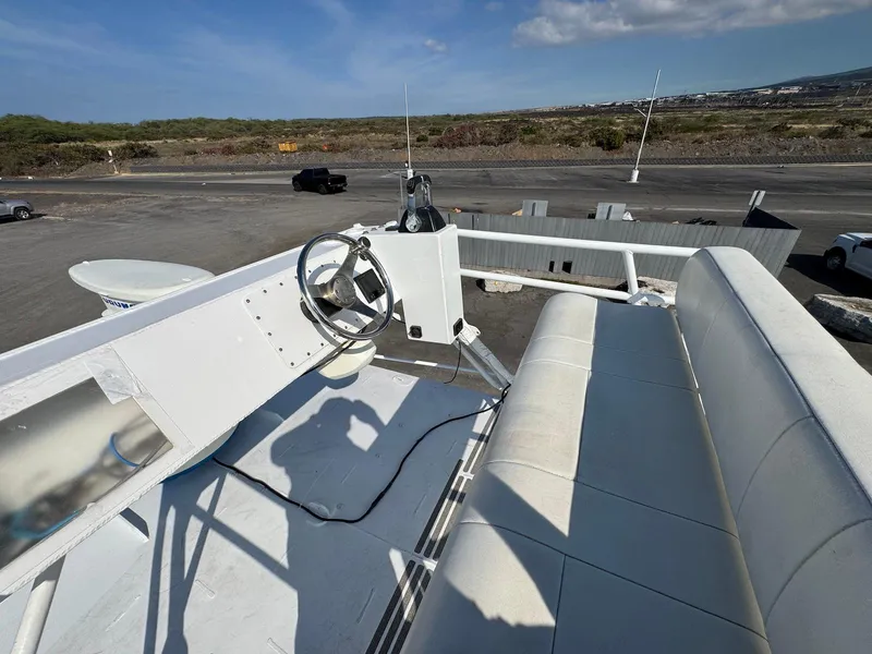 Slide: The Image of Helm of 2018 Custom Ocean Master boat with steering wheel and seating, parked on asphalt. - 16