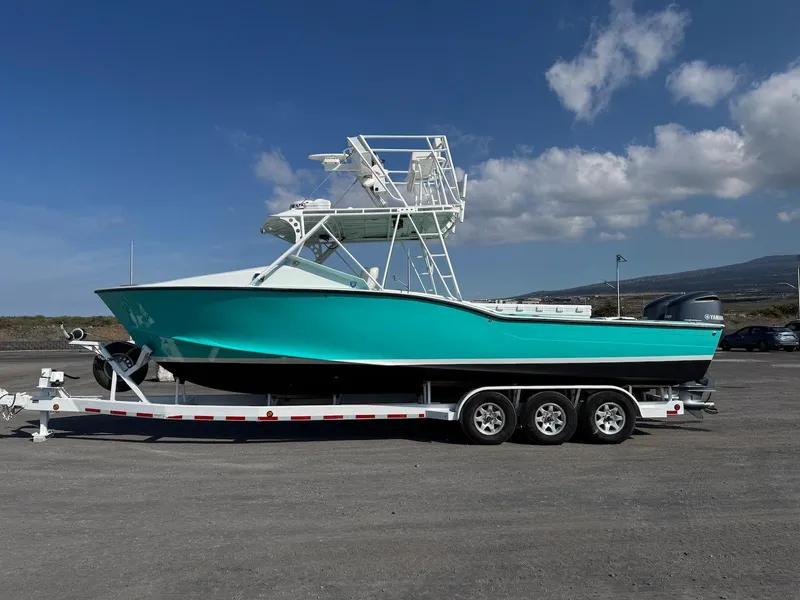 Slide: The Image of Custom 2018 Ocean Master boat on trailer, turquoise hull, clear sky background. - 8