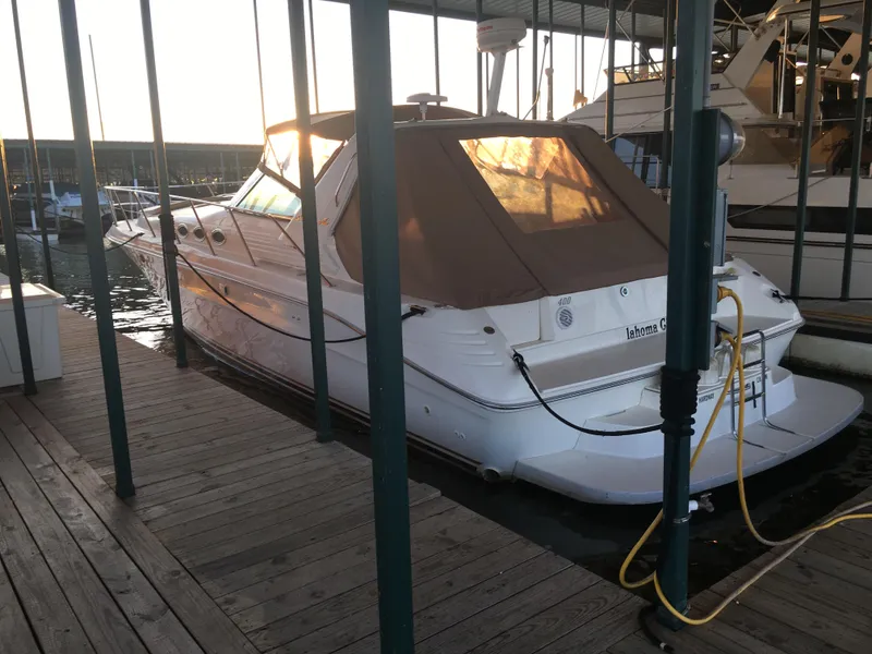 Slide: The Image of 1996 Sea Ray 400 Express Cruiser docked in marina, covered with brown canopy. - 2