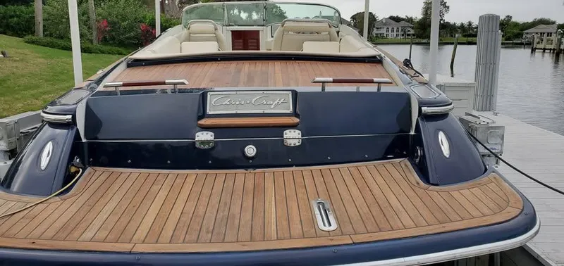 Slide: The Image of 2010 Chris-Craft Corsair 28 boat with teak deck, docked by a serene waterfront. - 10