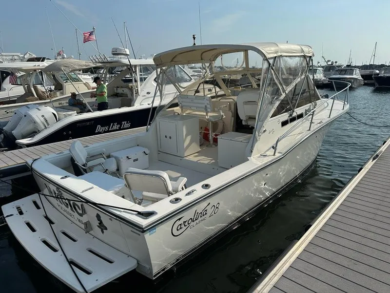 The Image of 2005 Carolina Classic 28 boat docked at marina, featuring spacious deck and canopy. - 0