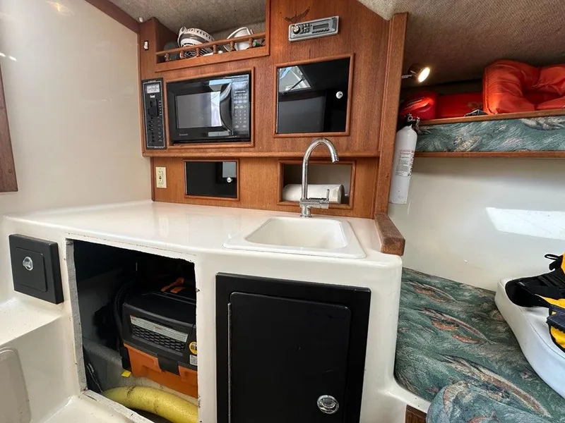 Slide: The Image of 2005 Carolina Classic 28 boat interior with kitchenette, sink, microwave, and storage compartments. - 10