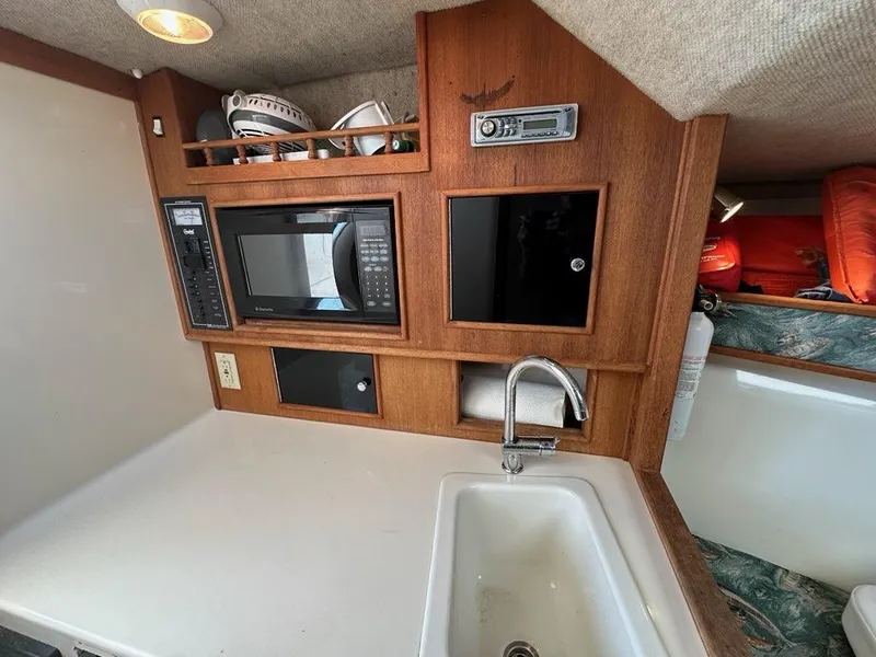 Slide: The Image of 2005 Carolina Classic 28 boat interior with sink, microwave, and storage. - 11