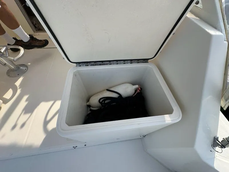 Slide: The Image of Open storage compartment on 2005 Carolina Classic 28 boat, containing a buoy and rope. - 23