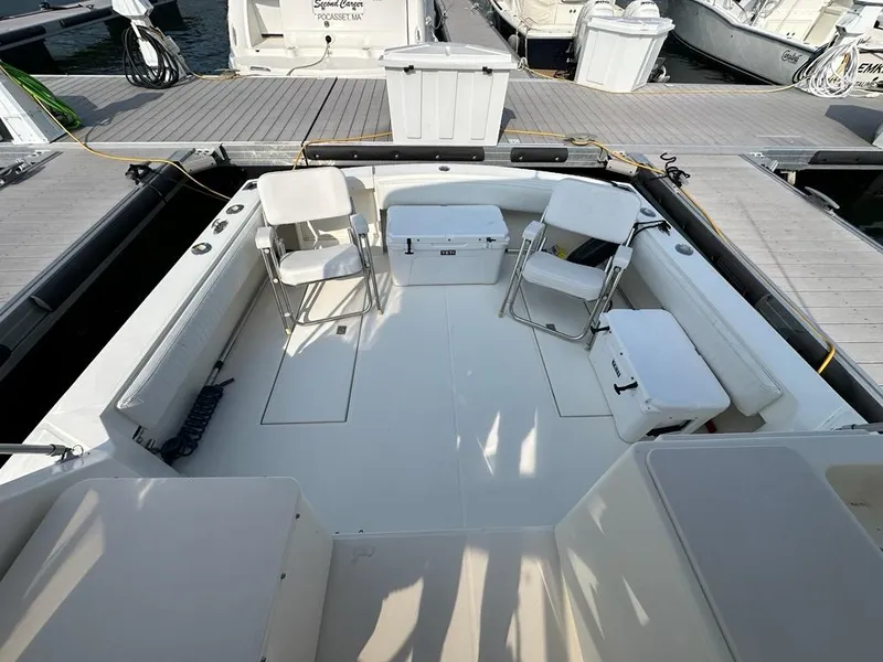 Slide: The Image of 2005 Carolina Classic 28 boat deck with chairs and coolers at a marina. - 25