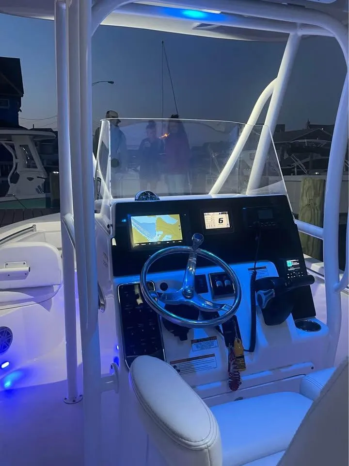 Slide: The Image of 2021 Cobia 220 Center Console boat interior with illuminated dashboard at dusk. - 10