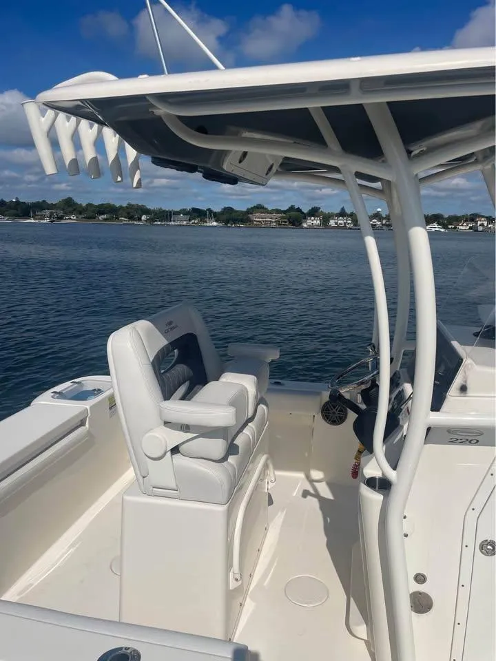 Slide: The Image of 2021 Cobia 220 Center Console boat on calm water, featuring a sleek design and comfortable seating. - 5