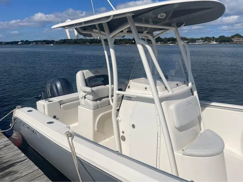 Slide: The Image of 2021 Cobia 220 Center Console boat docked on calm water under a blue sky. - 7
