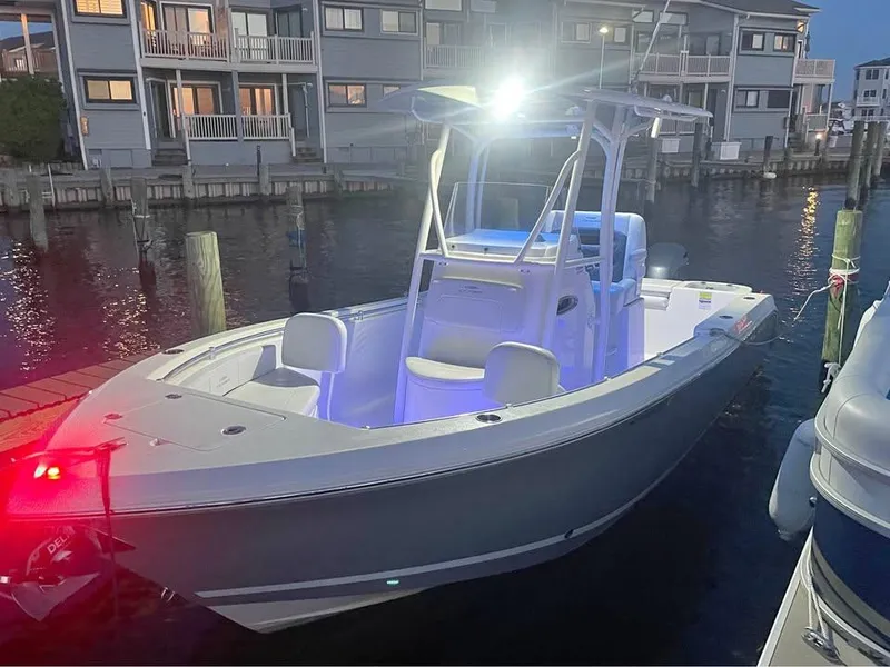Slide: The Image of 2021 Cobia 220 Center Console boat docked at night, illuminated by bright lights. - 8