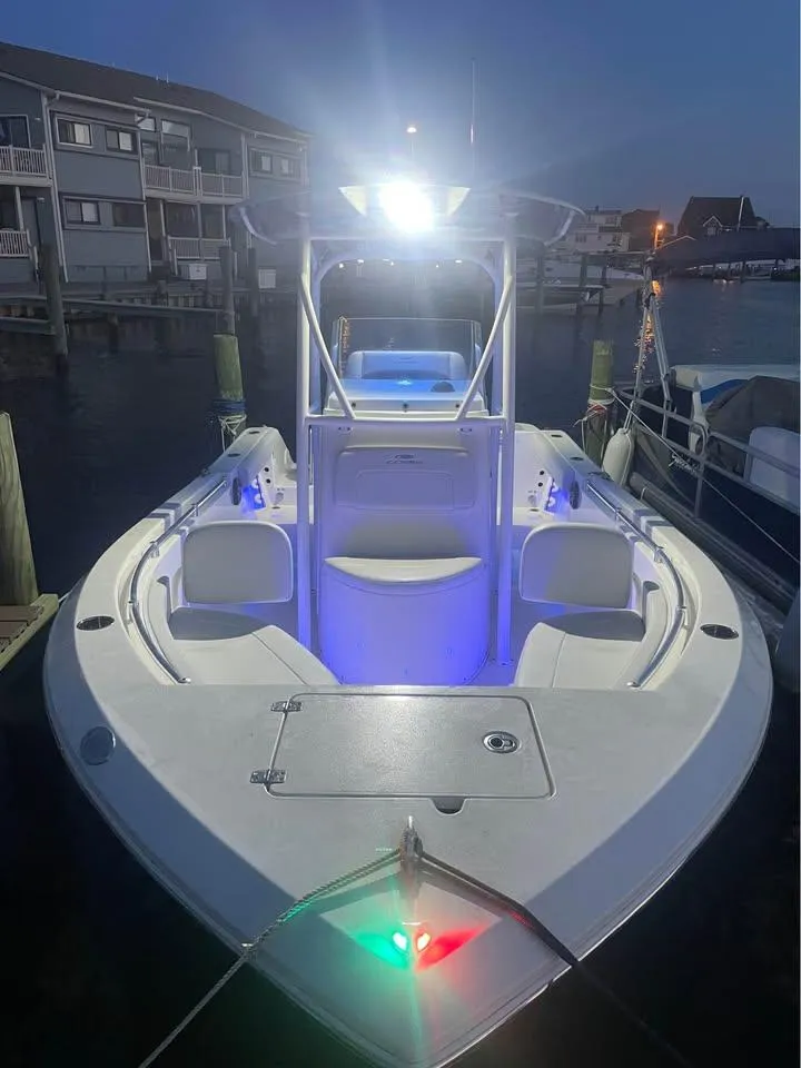 Slide: The Image of 2021 Cobia 220 Center Console boat illuminated at night in a marina. - 9