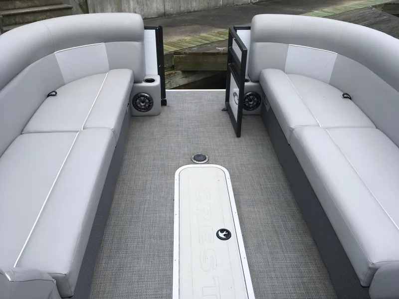 Slide: The Image of 2022 Crest Classic LX 240 pontoon boat interior with gray seating and speakers. - 22