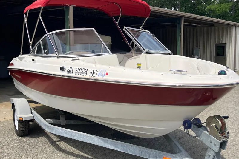 The Image of 2008 Maxum 1800SR boat with red canopy on trailer, parked outside a metal building. - 1