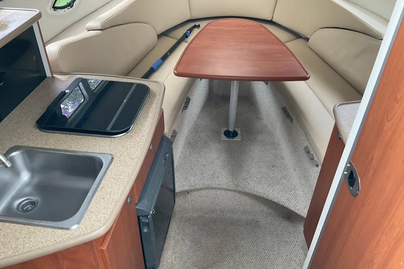 Slide: The Image of 2006 Bayliner 265 interior with kitchenette, sink, and cozy seating area. - 3