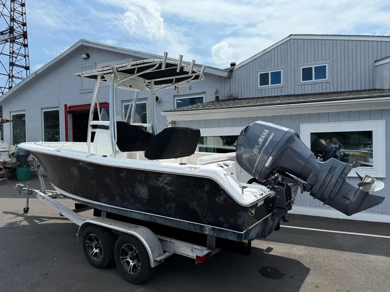 The Image of 2014 Sea Hunt Ultra 211 boat on trailer with Yamaha outboard motor, parked near building. - 0