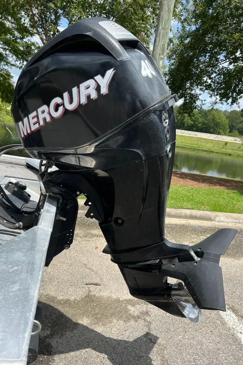Slide: The Image of Mercury outboard motor on 2012 Tracker Pro165 boat, parked near a pond. - 2