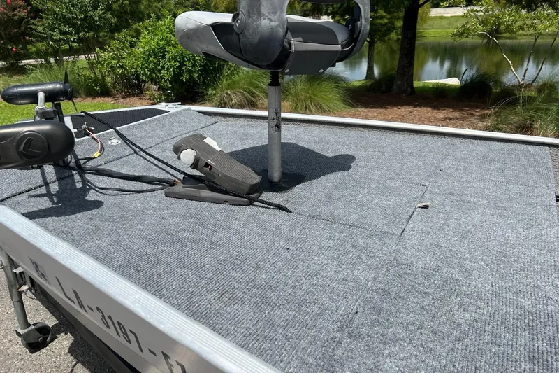 Slide: The Image of 2012 Tracker Pro165 boat deck with seat and trolling motor, near a pond. - 7