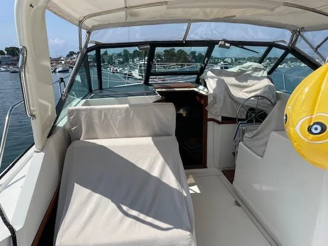Slide: The Image of 1990 Tiara Yachts 31 Open interior with covered seating and steering wheel, docked at marina. - 14