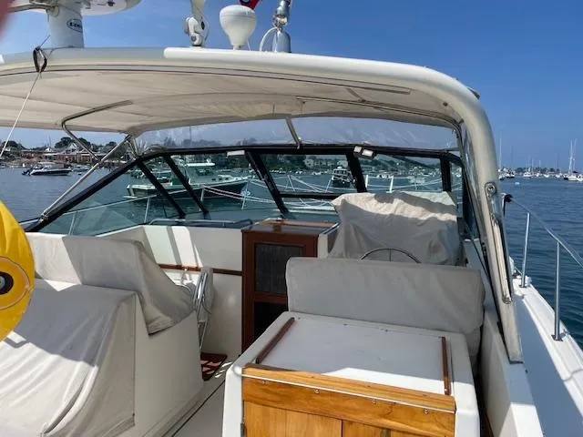 Slide: The Image of 1990 Tiara Yachts 31 Open boat interior with covered seating, docked in a marina. - 3