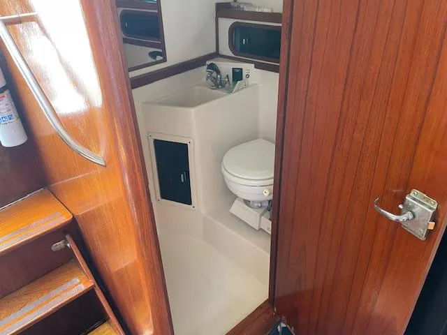 Slide: The Image of 1990 Tiara Yachts 31 Open bathroom with wooden door and compact toilet. - 8
