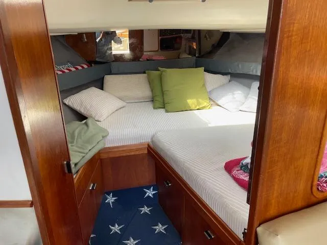 Slide: The Image of 1990 Tiara Yachts 31 Open cabin interior with cozy bedding and wooden cabinetry. - 9