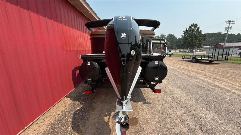 Slide: The Image of 2025 Regency 230 LE3 boat with powerful outboard motor, parked beside a red building. - 2