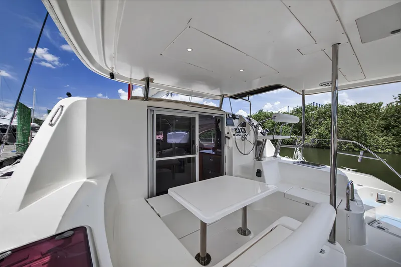 Slide: The Image of 2011 Leopard 38 catamaran cockpit with seating, table, and helm station under a clear sky. - 11