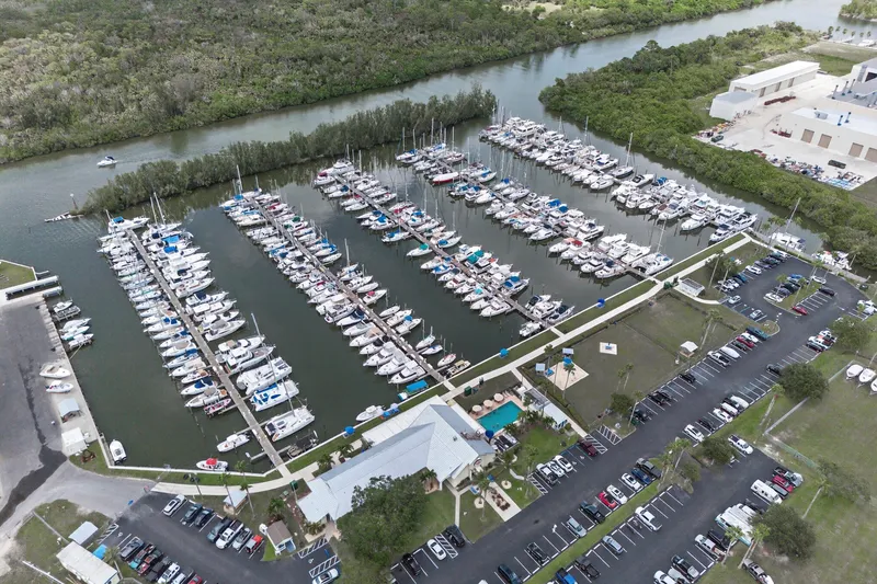 Slide: The Image of Aerial view of a marina with numerous boats docked, surrounded by lush greenery. - 115