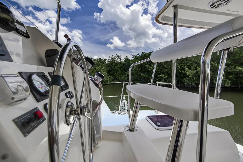 Slide: The Image of Steering wheel and controls of 2011 Leopard 38 yacht, with lush greenery and cloudy sky. - 23