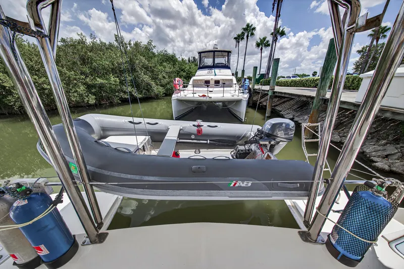 Slide: The Image of Leopard 38 catamaran with dinghy, docked in a lush marina, under a partly cloudy sky. - 35