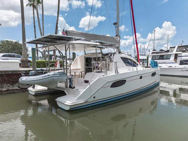 Slide: The Image of 2011 Leopard 38 catamaran docked in marina, clear sky, palm trees, and other boats visible. - 4