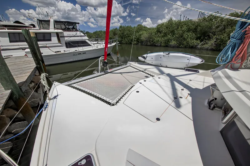 Slide: The Image of 2011 Leopard 38 catamaran docked, featuring spacious deck and netting under a sunny sky. - 41