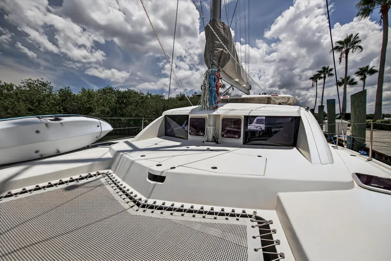 Slide: The Image of 2011 Leopard 38 catamaran docked, featuring spacious deck and sails under cloudy sky. - 43
