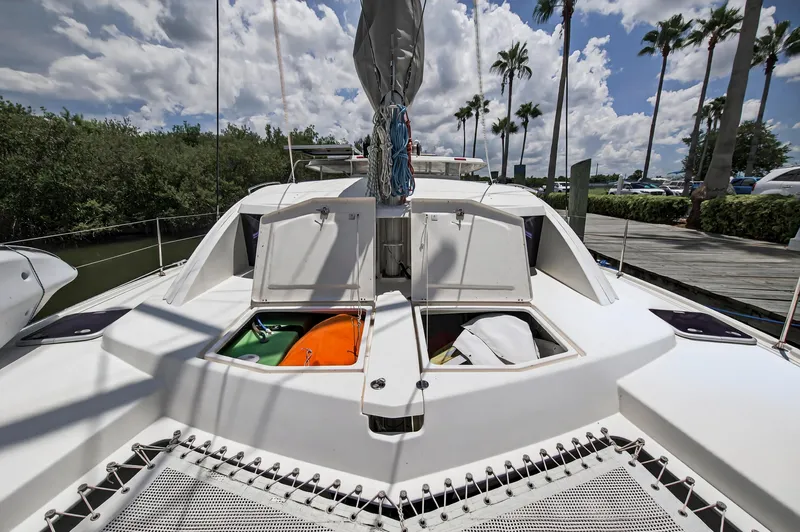 Slide: The Image of 2011 Leopard 38 catamaran deck with open storage compartments, docked near palm trees. - 46