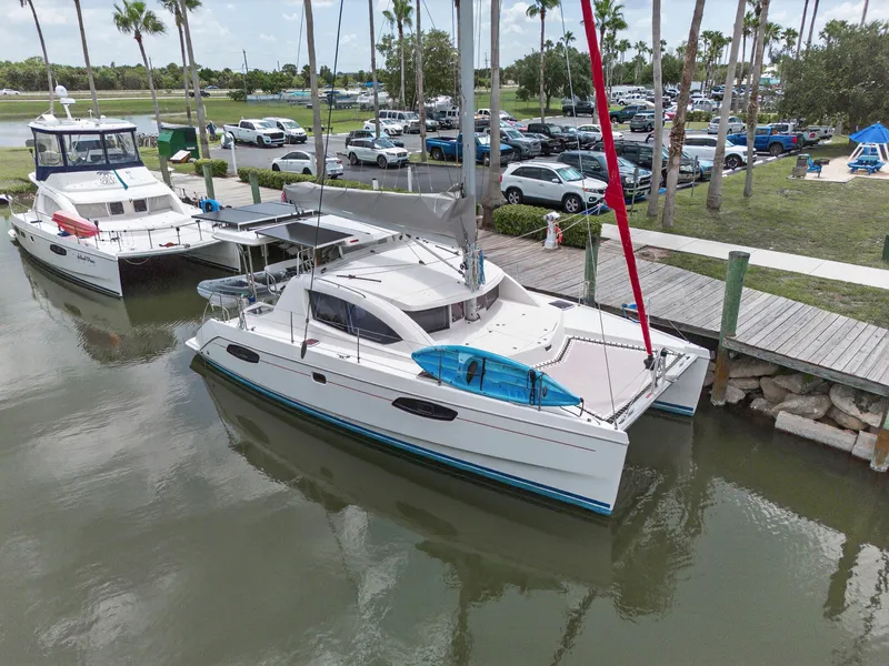 Slide: The Image of 2011 Leopard 38 catamaran docked near palm trees and parked cars. - 5