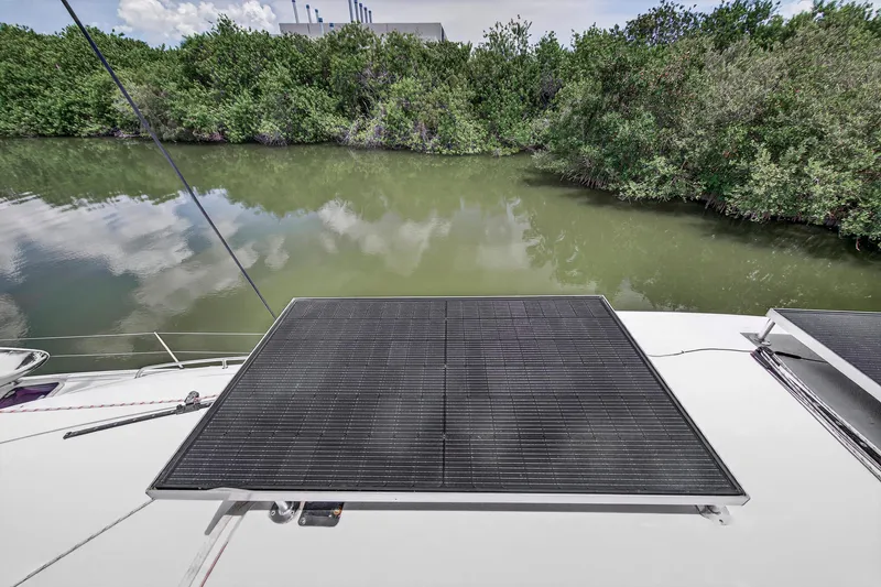 Slide: The Image of Solar panels on a 2011 Leopard 38 catamaran, docked by lush greenery and calm water. - 58