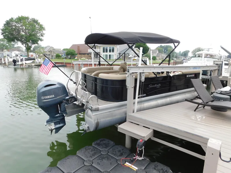 The Image of 2019 Godfrey SWEETWATER 2186 SB pontoon boat docked with Yamaha motor and American flag. - 2