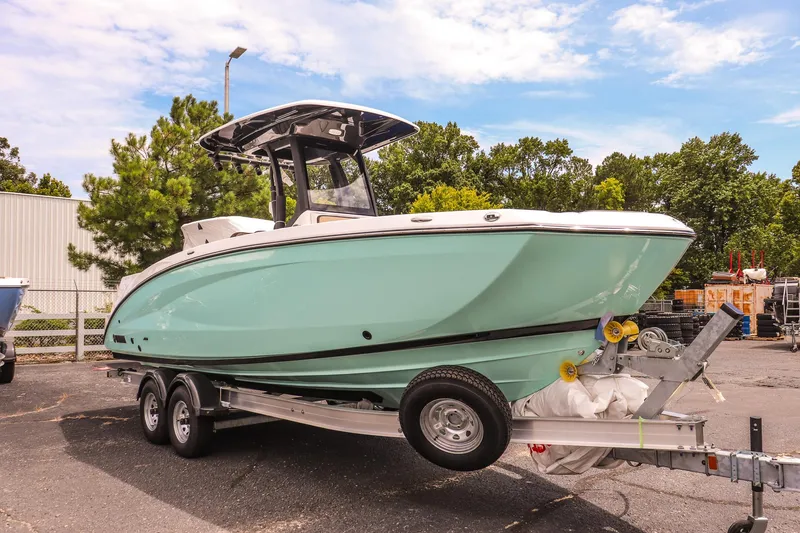 Slide: The Image of 2025 Yamaha Boats 255 FSH Sport E on trailer, mint green hull, outdoor setting. - 2