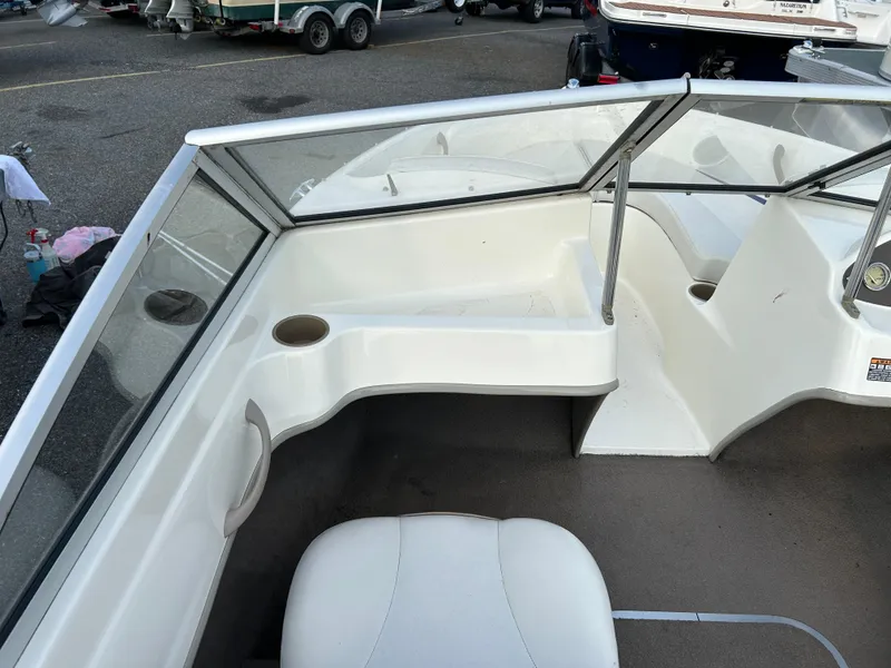 Slide: The Image of 2003 Bayliner 175 Bowrider interior with seating and cup holder, parked in a marina. - 6