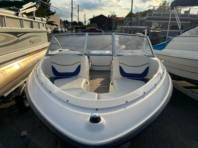 Slide: The Image of 2003 Bayliner 175 Bowrider boat with white and blue seating, parked outdoors. - 7