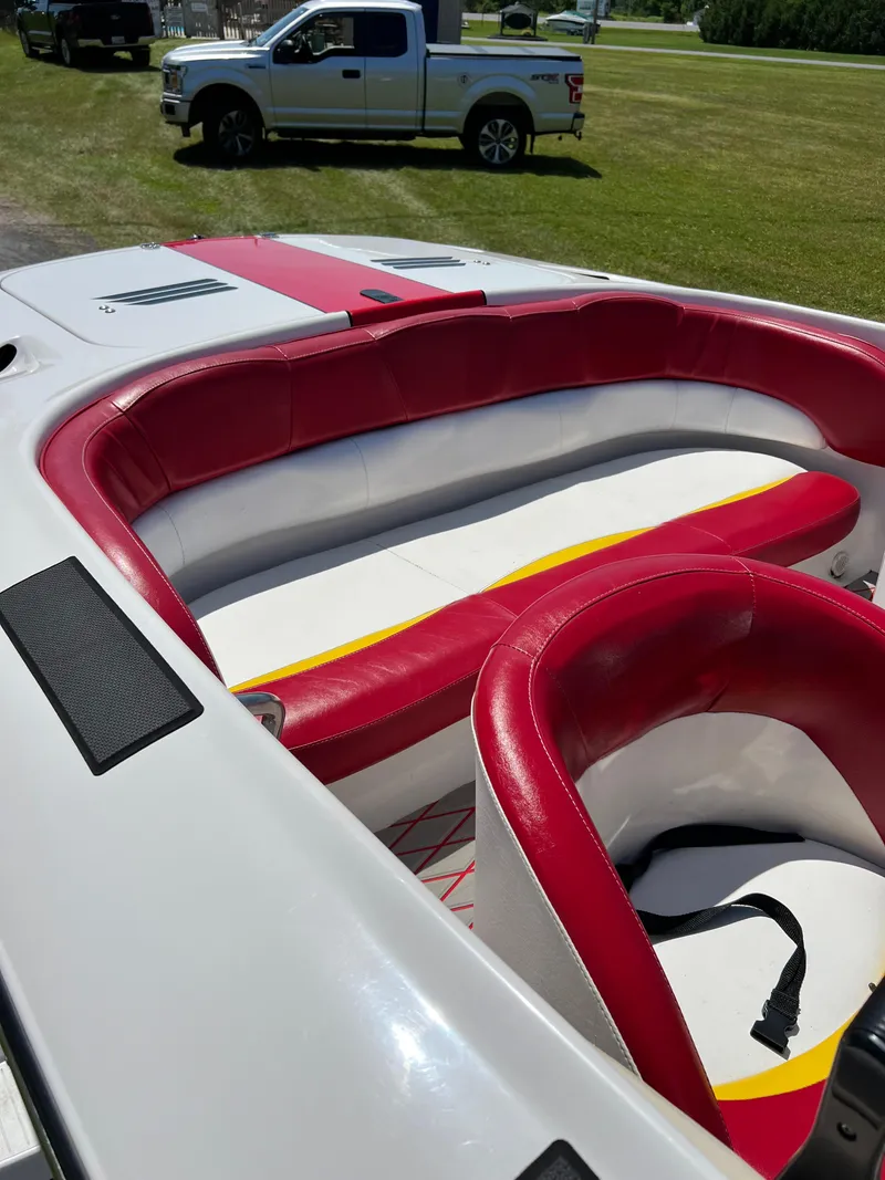 Slide: The Image of 1997 Four Winns U17 boat interior with red and white seating, parked on grass. - 2